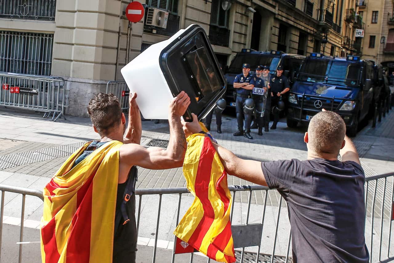  A demonstrator holds a ballot box in front of police officers during a protest against the decision by the Spanish Supreme Court.