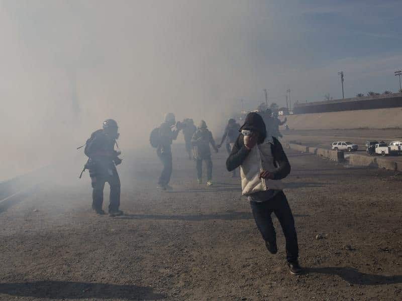 Migrants run from tear gas launched by US agents