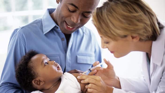 Doctor giving injection to baby boy (2-5 months)
