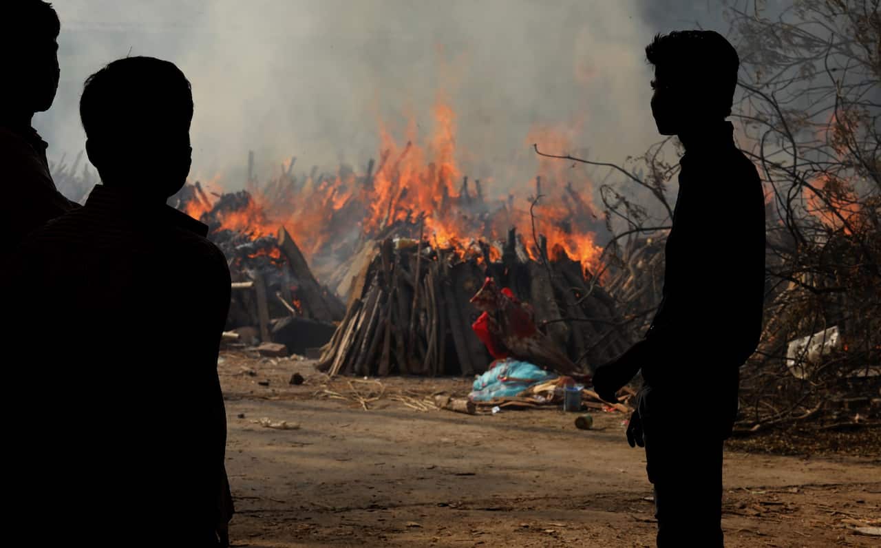 Family members look on as COVID-19 victims are cremated in New Delhi 
