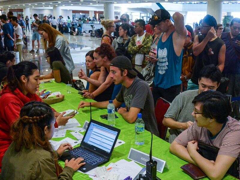 Stranded tourists line up to change their return ticket in Denpasar