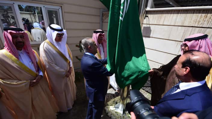 Iraqi Foreign Minister Mohamad Ali Alhakim (C) raises the Saudi national flag during the reopening ceremony of the Saudi consulate in Baghdad