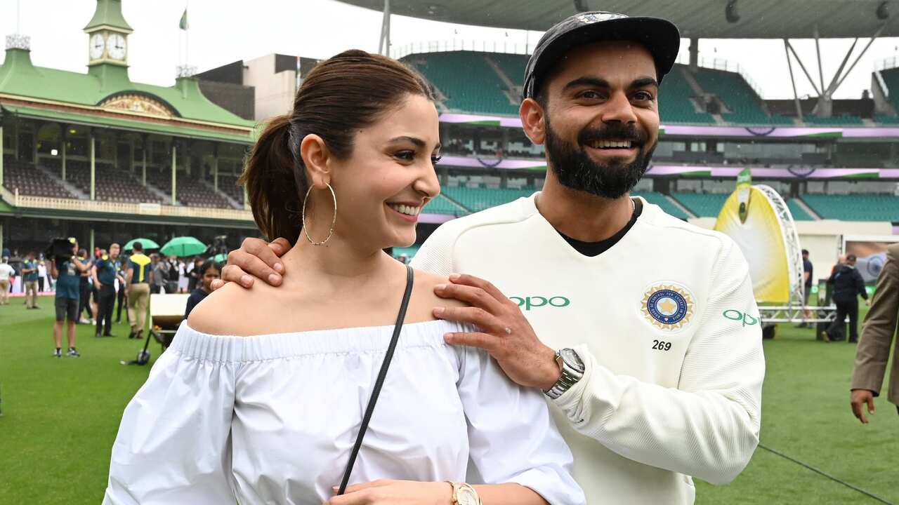India's captain Virat Kolhi and his wife Anushka Sharma walk on the field as they celebrate India's test series win.