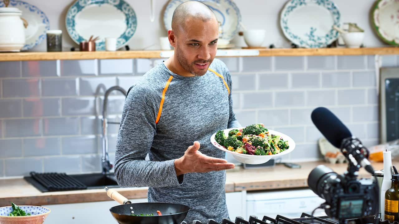 A man holding vegetarian food and talking to video camera