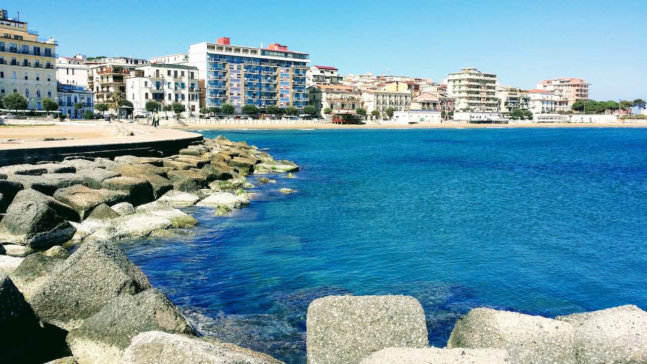 Buildings By Sea Against Blue Sky