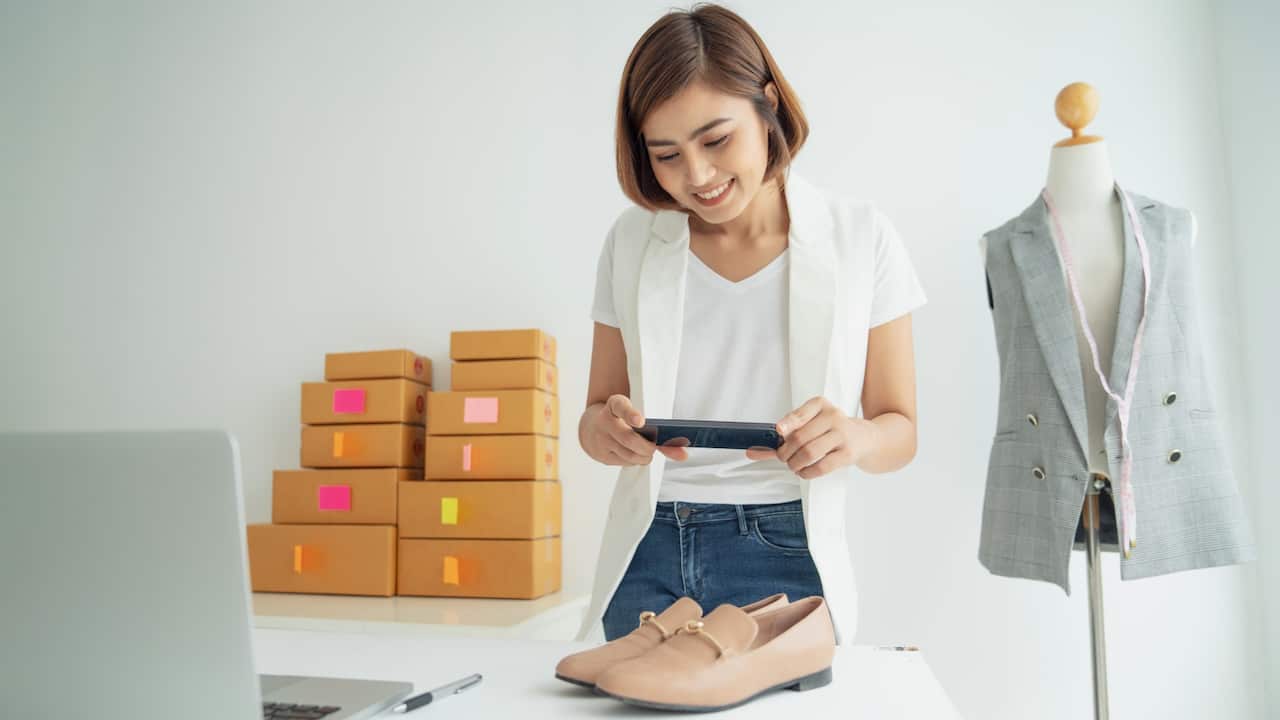 A young woman taking photo of shoes with a smartphone digital camera