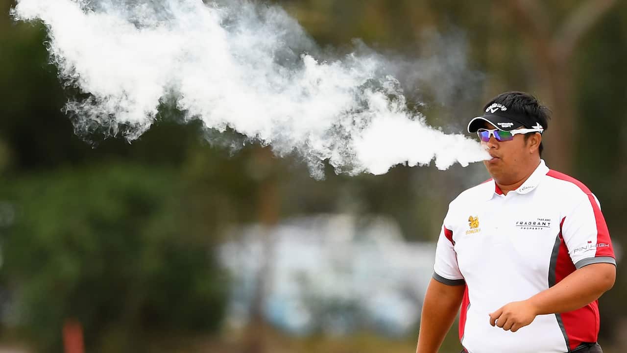 Kiradech Aphibarnrat of Thailand smokes an electric cigarette during the World Cup of Golf at Kingston Heath Golf in Melbourne in 2019.