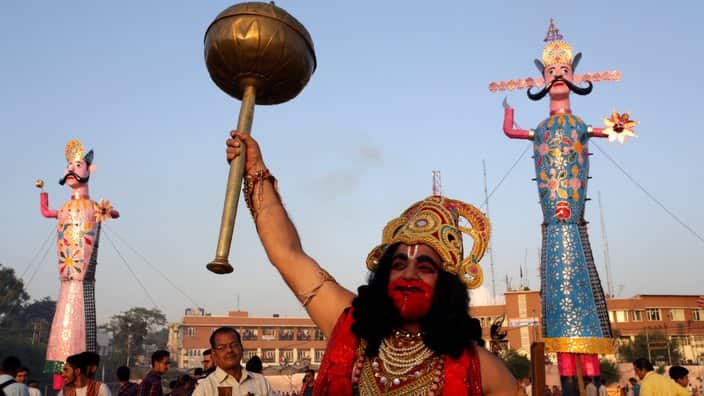 An Indian devotee dressed as Hindu God Hanuman stands in front of the effigies of demon king Ravana and Kumbhkarana during the Dussehra festival celebrations