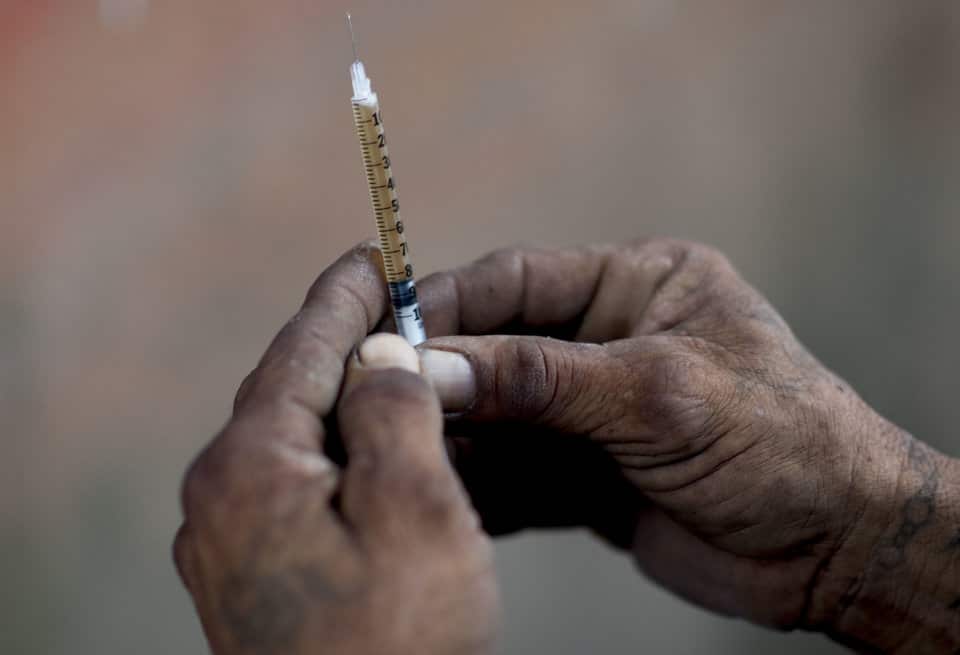 A heroin addict prepares a dose