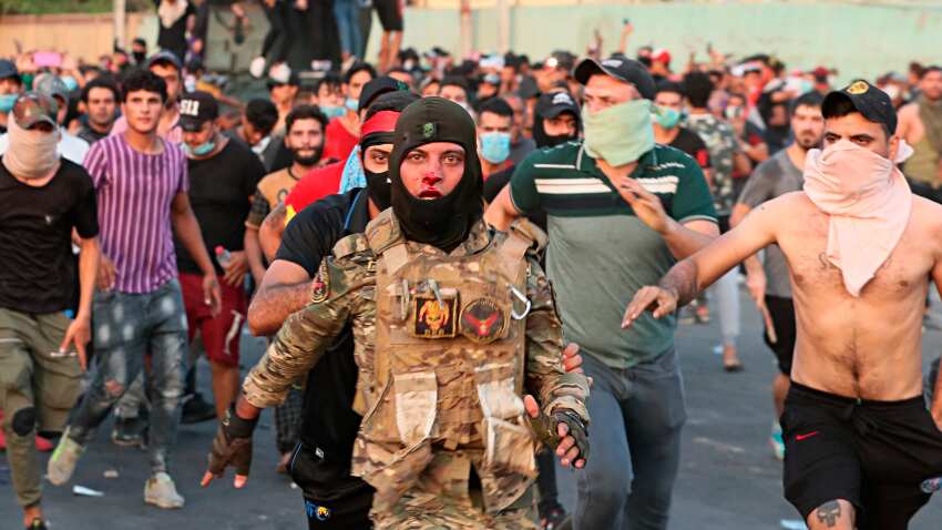 Anti-government protesters help a soldier from the Federal Police Rapid Response Forces to get out of the protest site area after other protesters beat him, in Baghdad, Iraq,