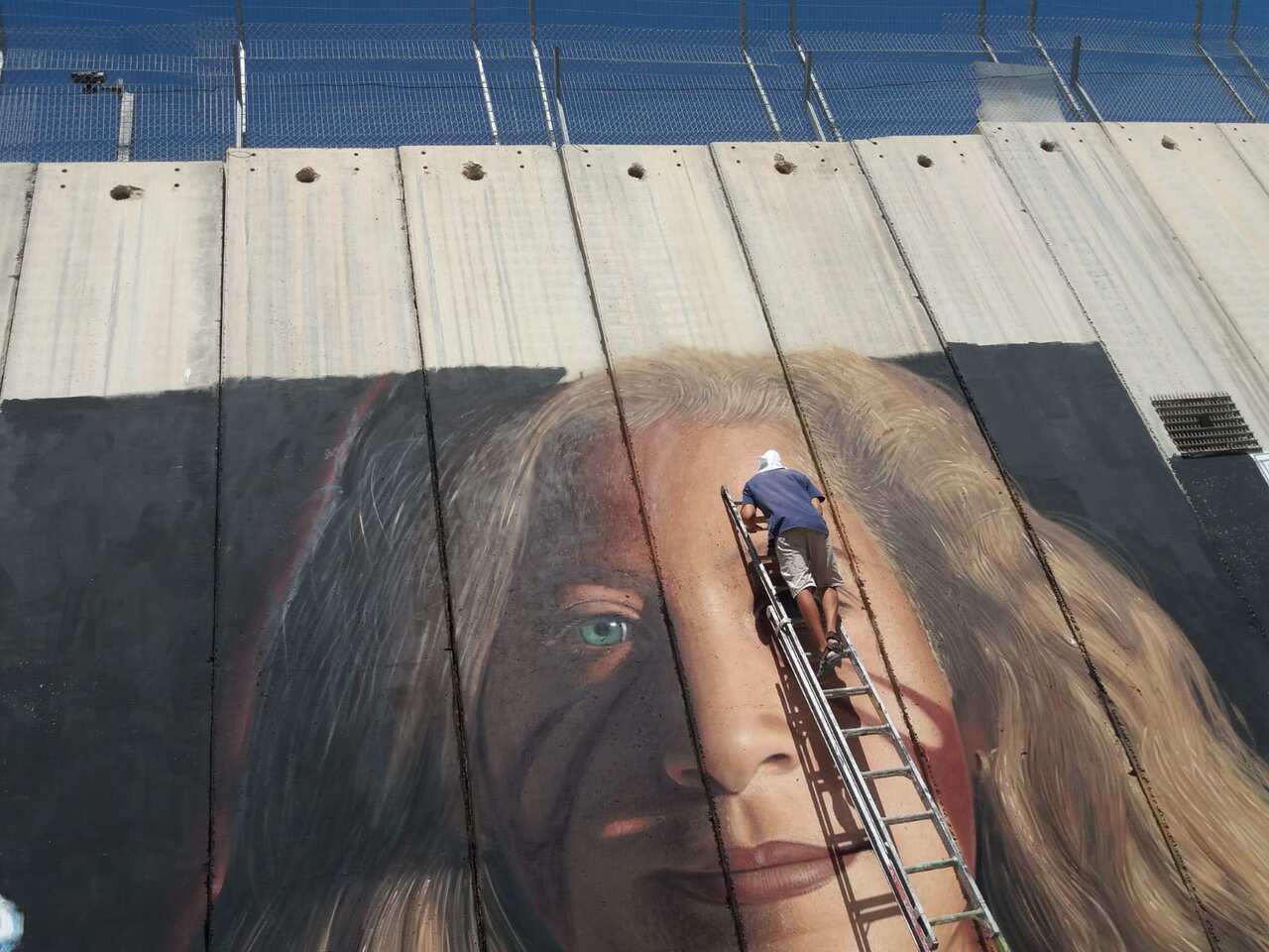 Italian Artist Jorit painting a portrait of Ahed Tamimi