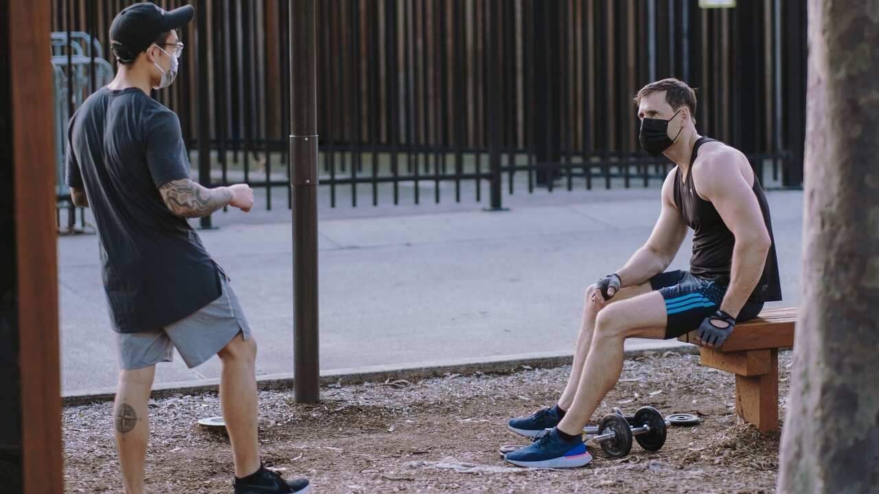 Two man in face masks working out in the park during a coronavirus lockdown