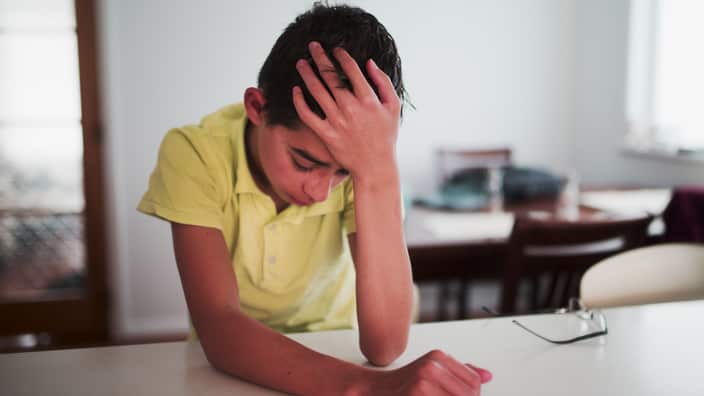 Crying Mixed Race boy with hand on head
