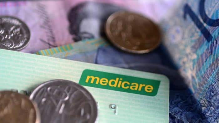 Bank notes and coins are seen with a Medicare Card in Brisbane, Wednesday, May 1, 2013. Prime Minister Julia Gillard today announced a levy to fund the National Disability Insurance Scheme. (AAP Image/Dave Hunt) NO ARCHIVING