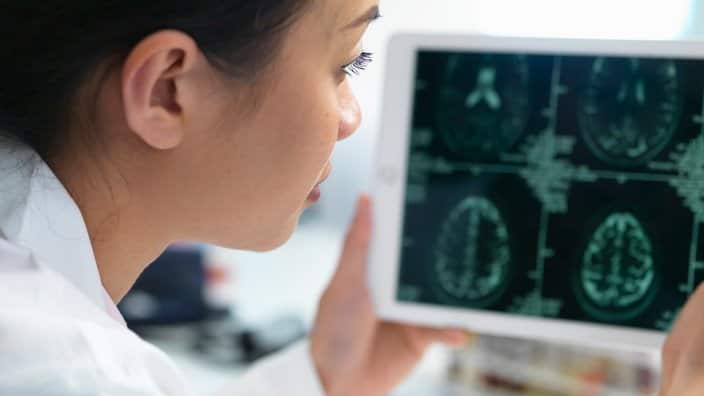 Doctor viewing CT scan result of brain on digital tablet for abnormalities