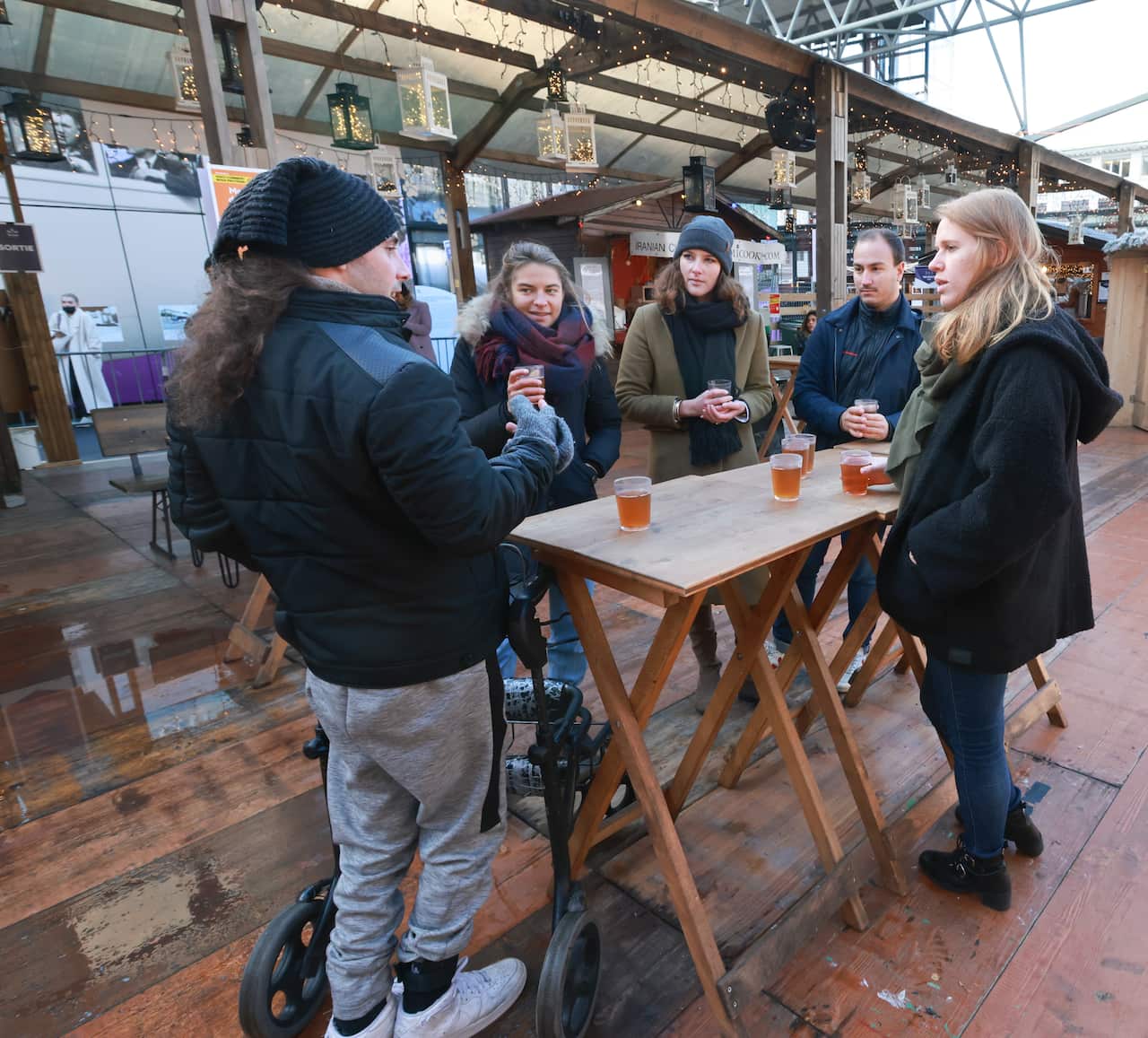 Michel Roccati standing up and having a beer with others.