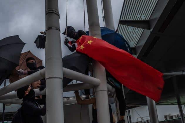 Protestors take down a national Chinese flag in Hong Kong. NYTNS