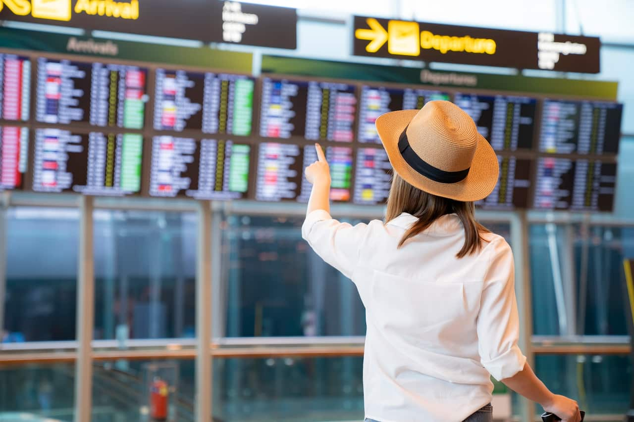 Female passenger looking flight schedule on the digital board in the terminal