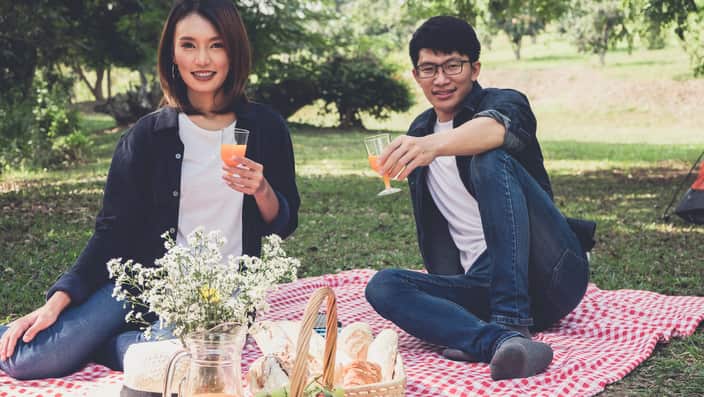 Portrait Of Young Friends Sitting On Picnic Blanket At Park