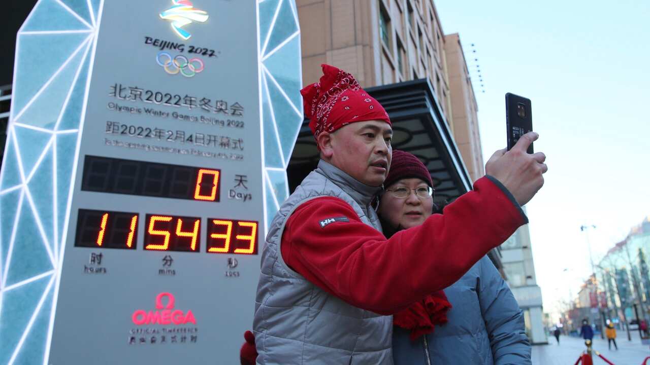 The countdown clock indicates the time until the opening ceremony of the Beijing Winter Olympics in Beijing, on February 4, 2022. Local people take selfies.