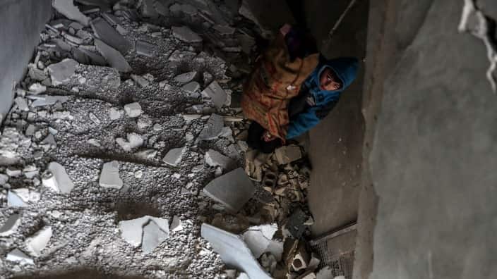 A boy inspects the rubble of a damaggot killed in Douma