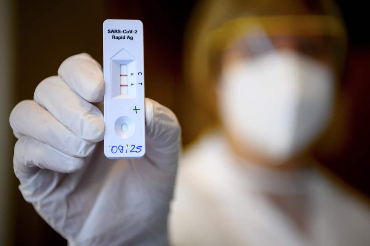 A health worker shows a positive result from a Rapid Antigen Test