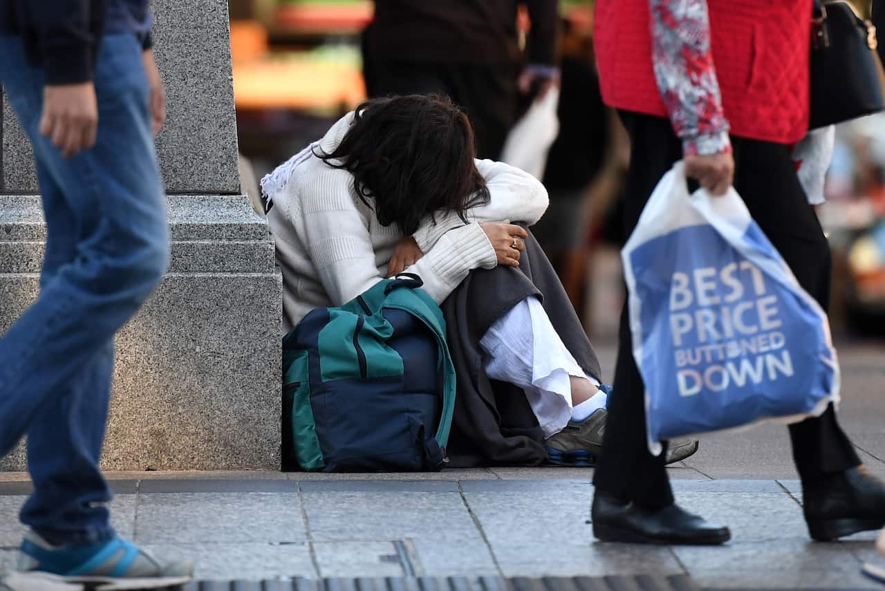 A homeless woman sits on a street corner in central Brisbane, Friday, June 9, 2017. (AAP Image/Dan Peled) NO ARCHIVING