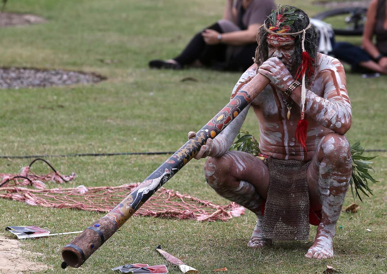 An Aboriginal man plays a didgeridoo d