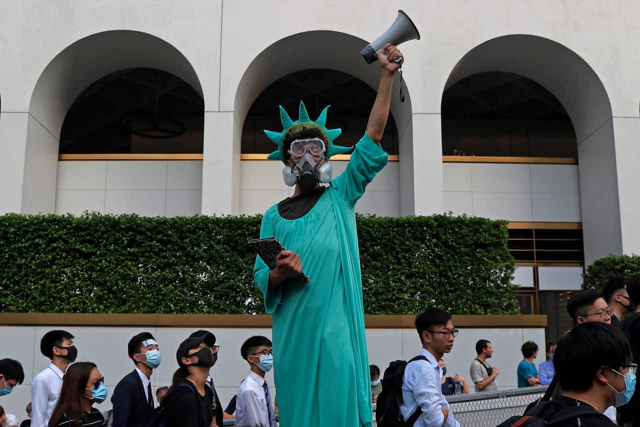 A protester dressed as the Statue of Liberty poses as people march past from Charter Garden to the U.S. Consulate in Hong Kong,