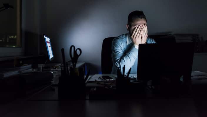 Exhausted businessman sitting at desk in office at night