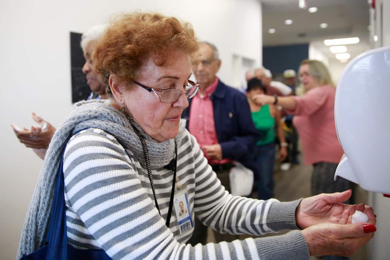 A woman uses hand sanitizer before eating lunch, as coronavirus poses a challenge for nursing homes and the elderly