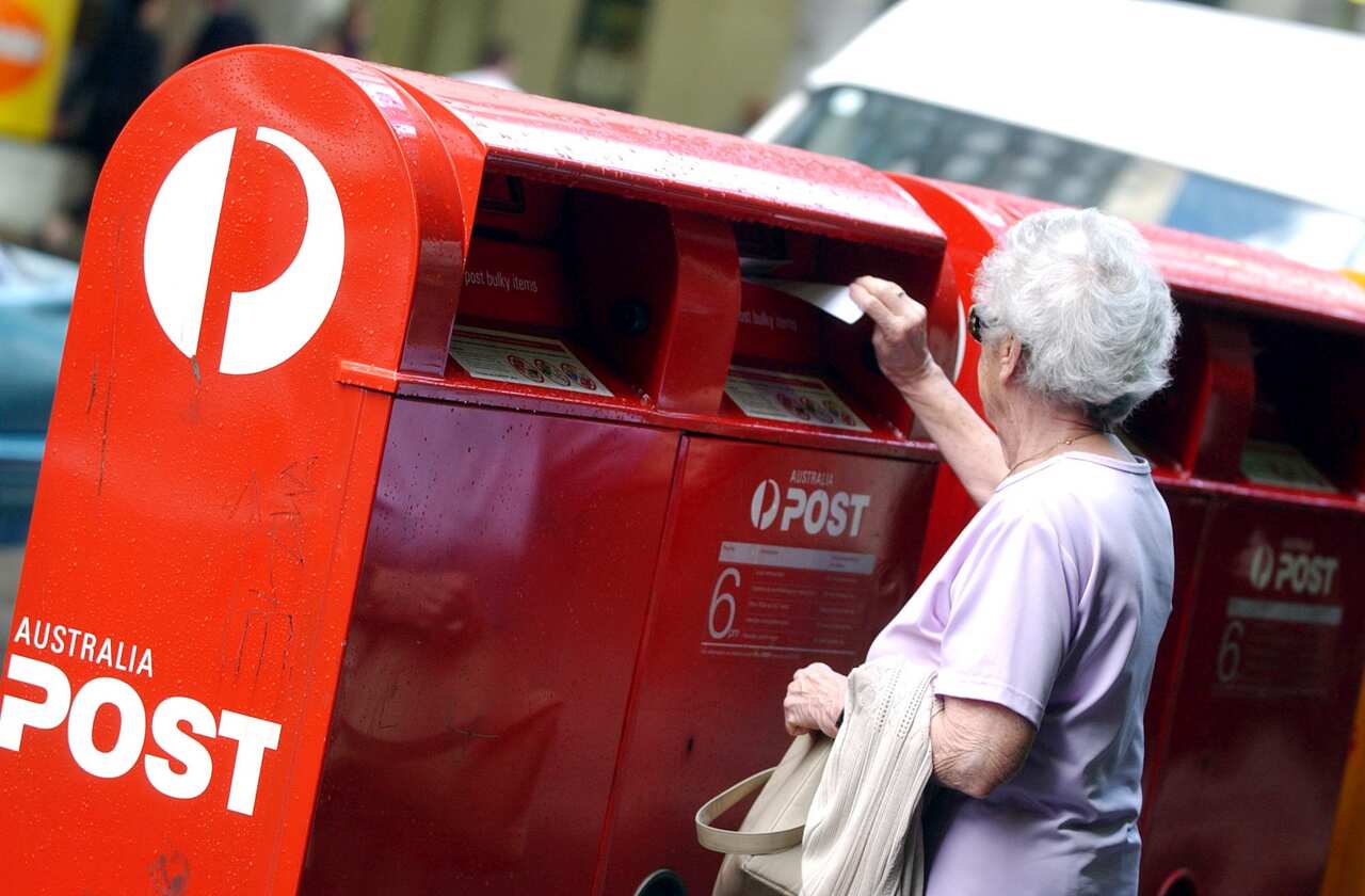 A woman posts a letter in one of the Australian post boxes in the city of Sydney.  (AAP Image/Dean Lewins). NO ARCHIVING.