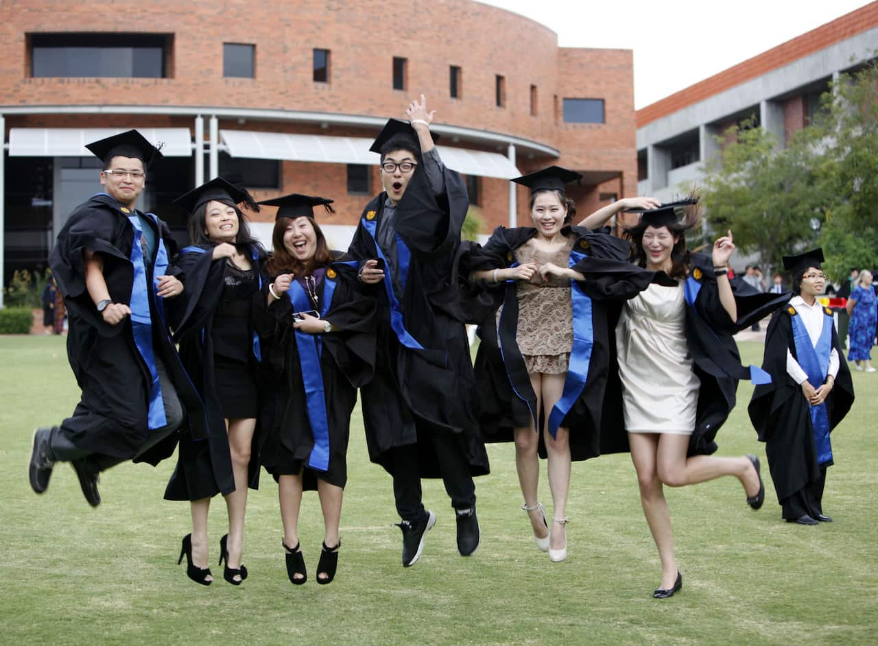 Chinese students studying at Curtin University in Perth pose during a graduation photo shoot (AAP).