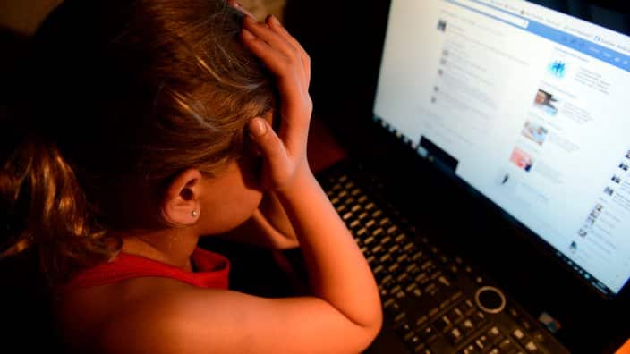 An  upset young girl in front of a personal computer  in Brisbane