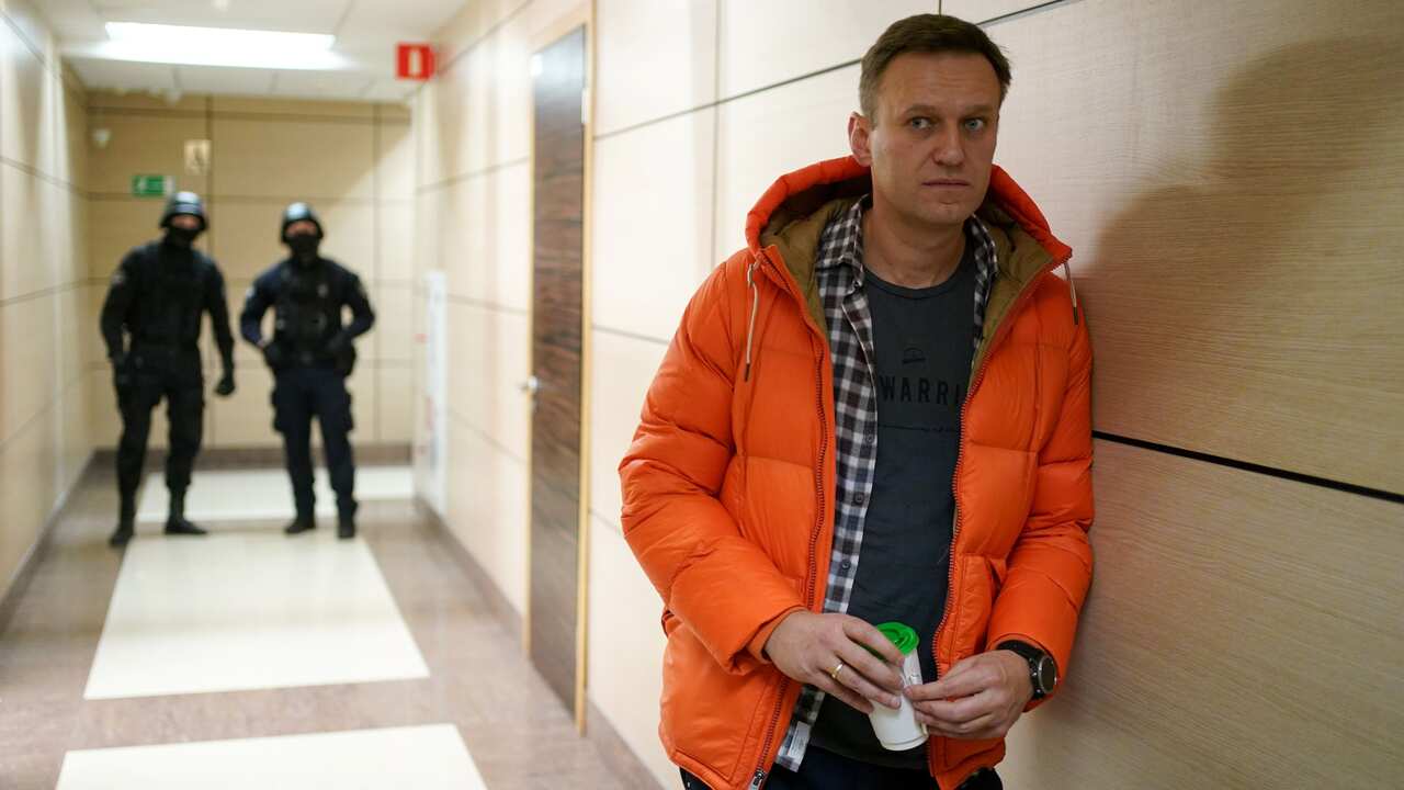 TOPSHOT - Russian opposition leader Alexei Navalny stands near law enforcement agents in a hallway of a business centre, which houses the office of his Anti-Corruption Foundation (FBK), in Moscow on December 26, 2019. -