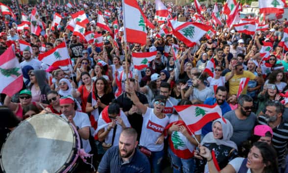 Protesters wave flags during a protest in front of the government palace in downtown Beirut, Lebanon.