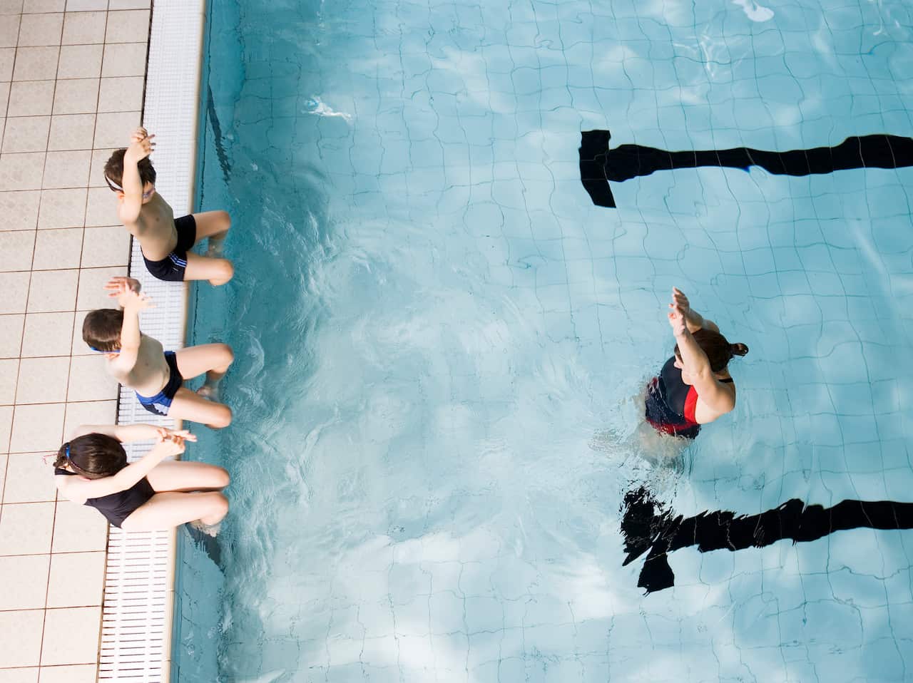 Swimming coach teaching children.