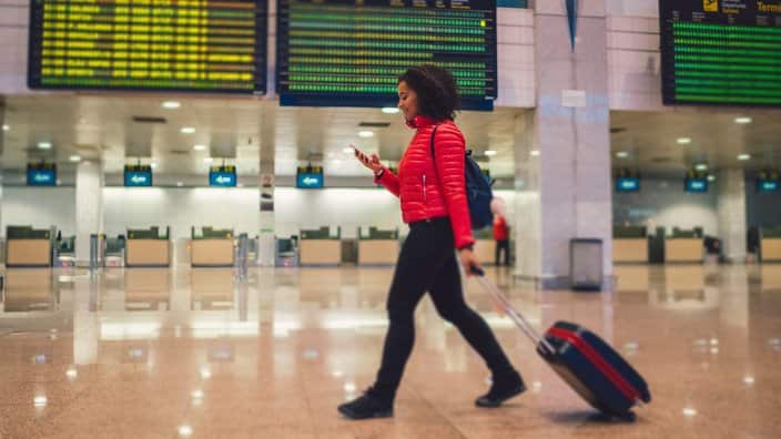 Mixed race woman texting at the airport terminal