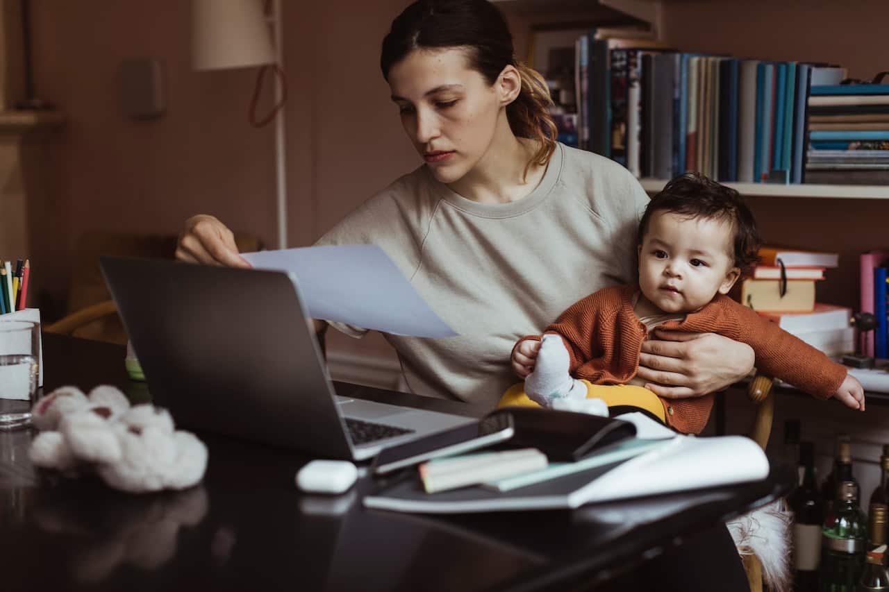 Female professional reading document while sitting with male toddler at home