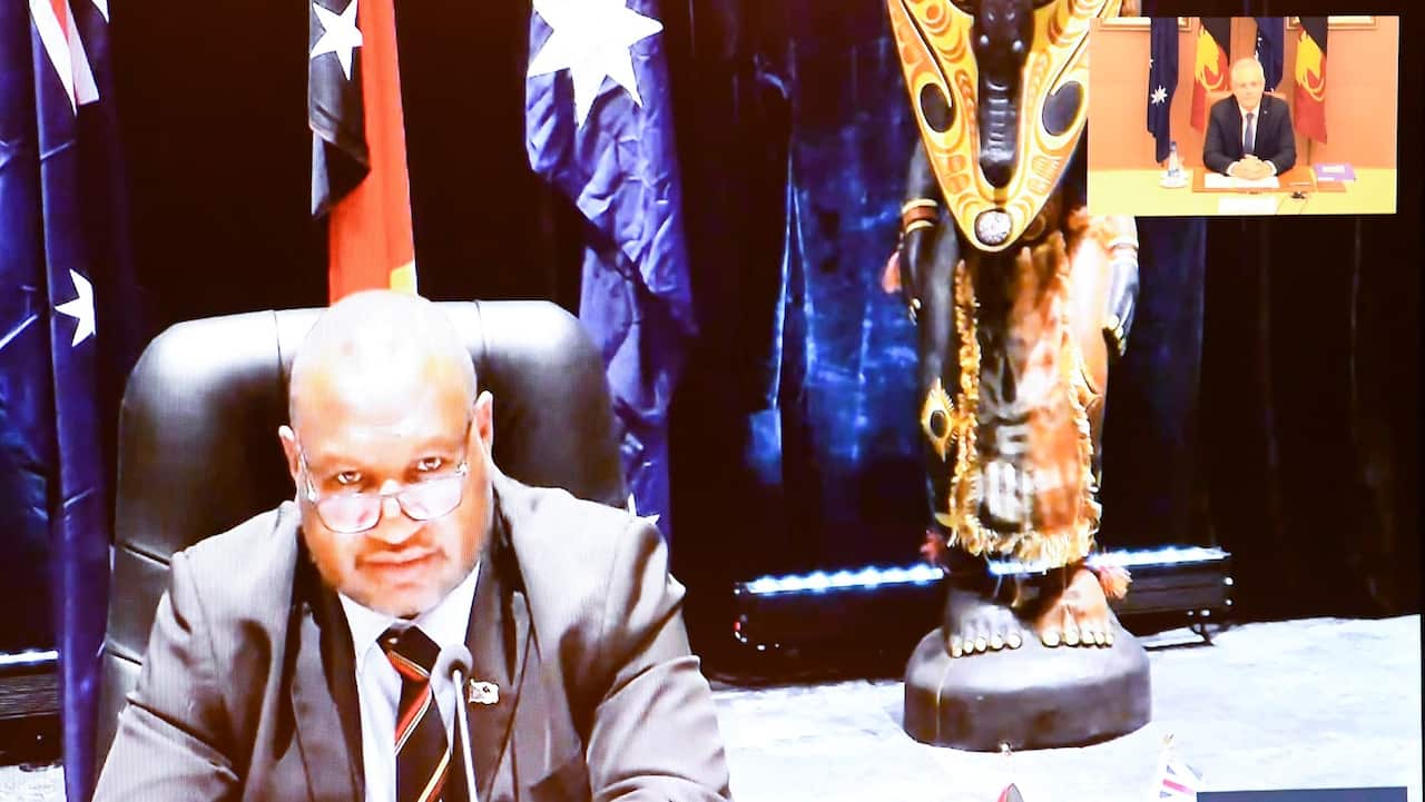 Australian Prime Minister Scott Morrison and the Prime Minister of Papua New Guinea James Marape are seen on a TV screen during a virtual summit on health, investment and security at Parliament House in Canberra, Wednesday, August 5, 2020.