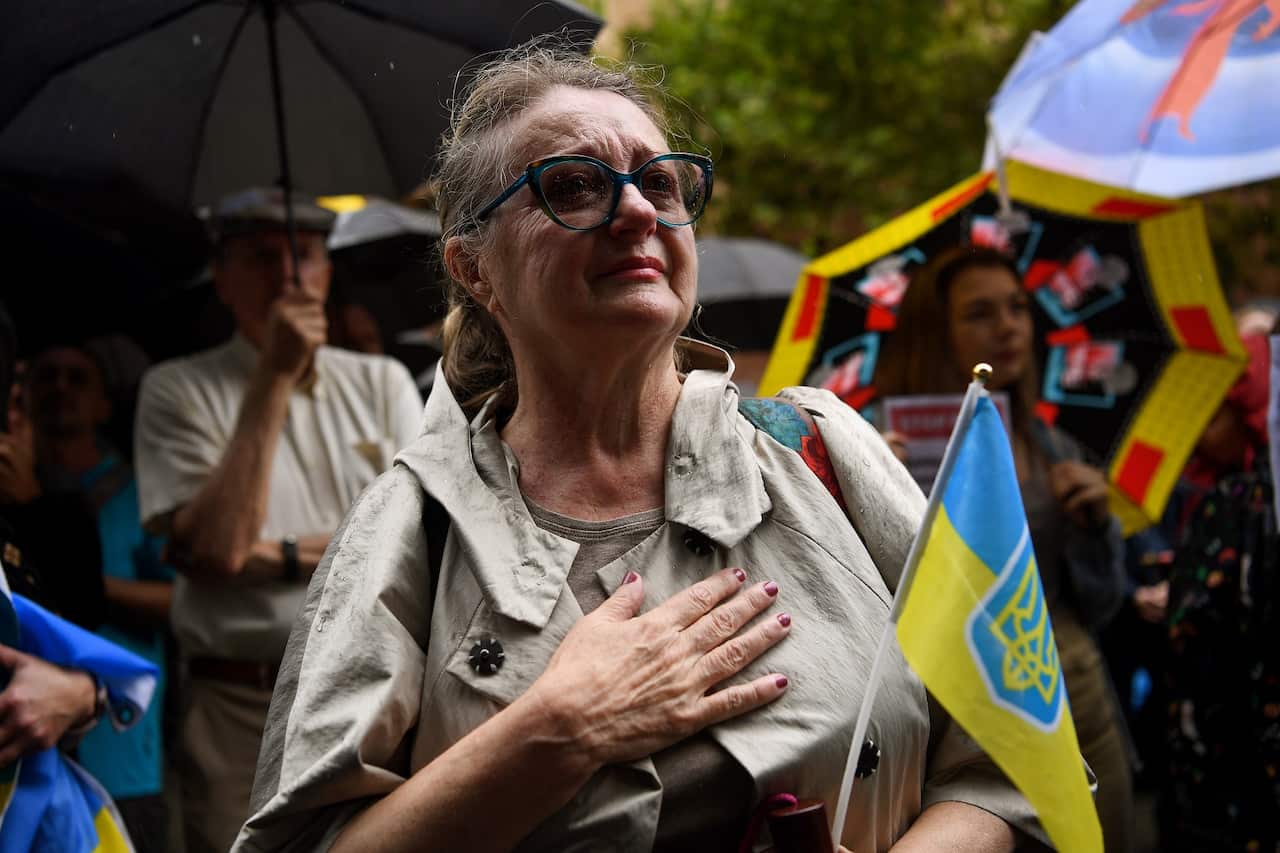 Protesters hold placards and Ukrainian flags during a rally against the war in Ukraine at Martin Place in Sydney, Friday, February 25, 2022. (AAP Image/Bianca De Marchi) NO ARCHIVING