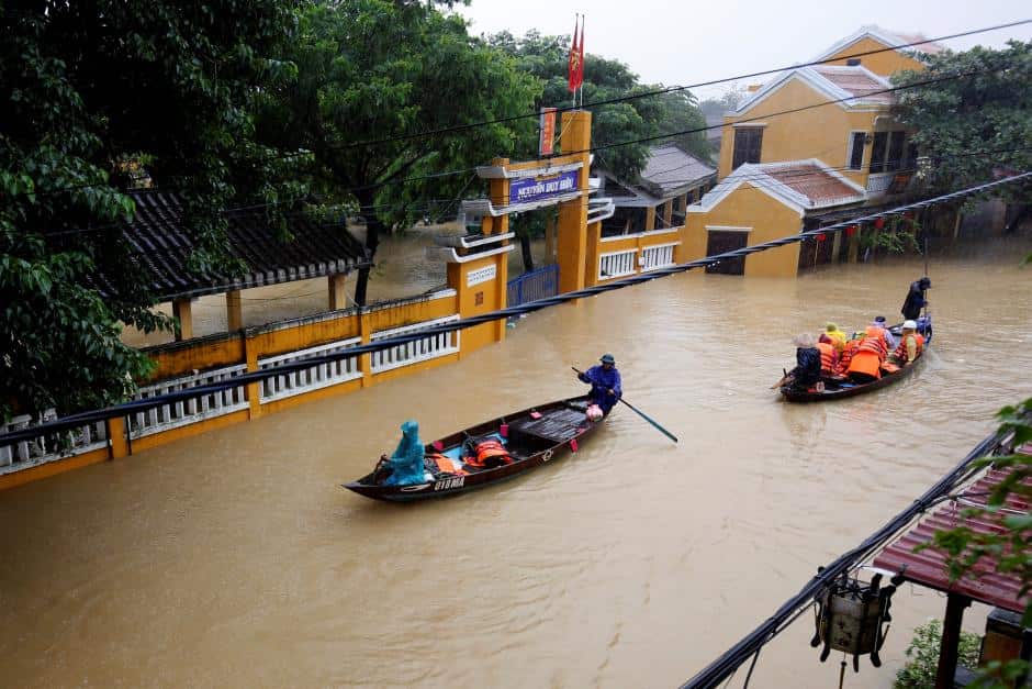 People ride a boat along submerged houses in UNESCO heritage ancient town of Hoi An after typhoon Damrey hits Vietnam