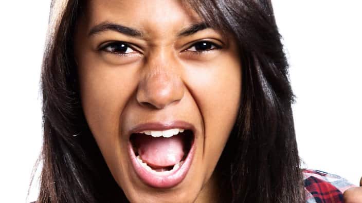 Young woman clenches fists and yells, either encouraging or furious