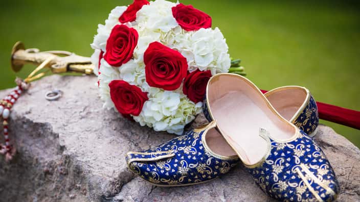 Traditional Sikh wedding sword and grooms shoes with a bridal bouquet.