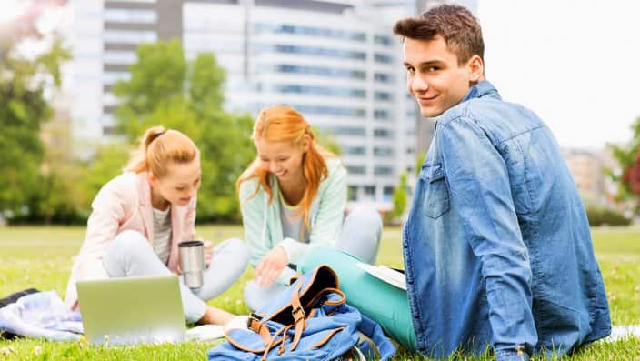 Portrait of young man with female friends studying on university campus