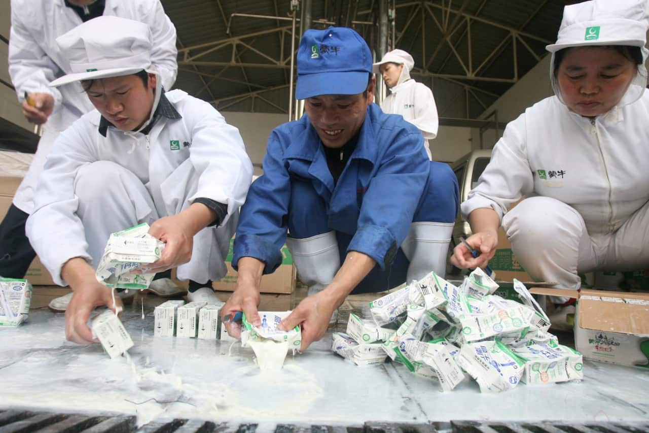 Workers squeeze melamine-tainted milk into a drainage ditch leading to the sewage treatment plant at a Mengniu Dairy factory in Wuhan in central China, 2008.