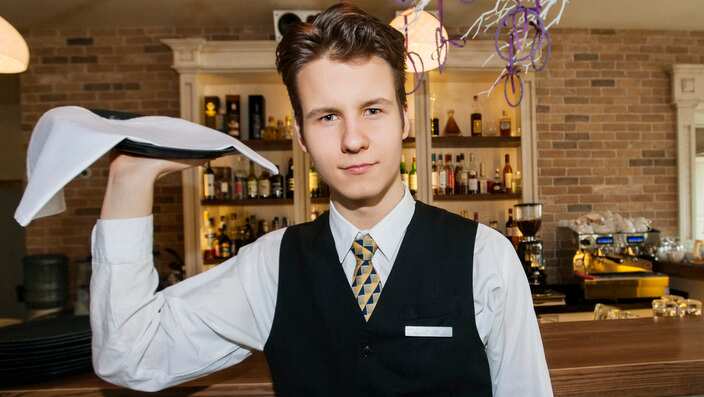 Portrait of confident waiter carrying serving tray in restaurant