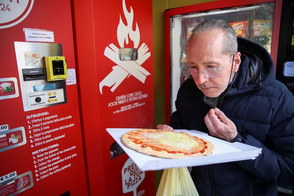 Claudio Zampiga sniffs his pizza at the first automatic pizza vending machine