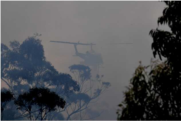 A water bombing helicopter helps to contain the Gospers Mountain Fire as it burns towards the village of Bilpin North West of Sydney AAP