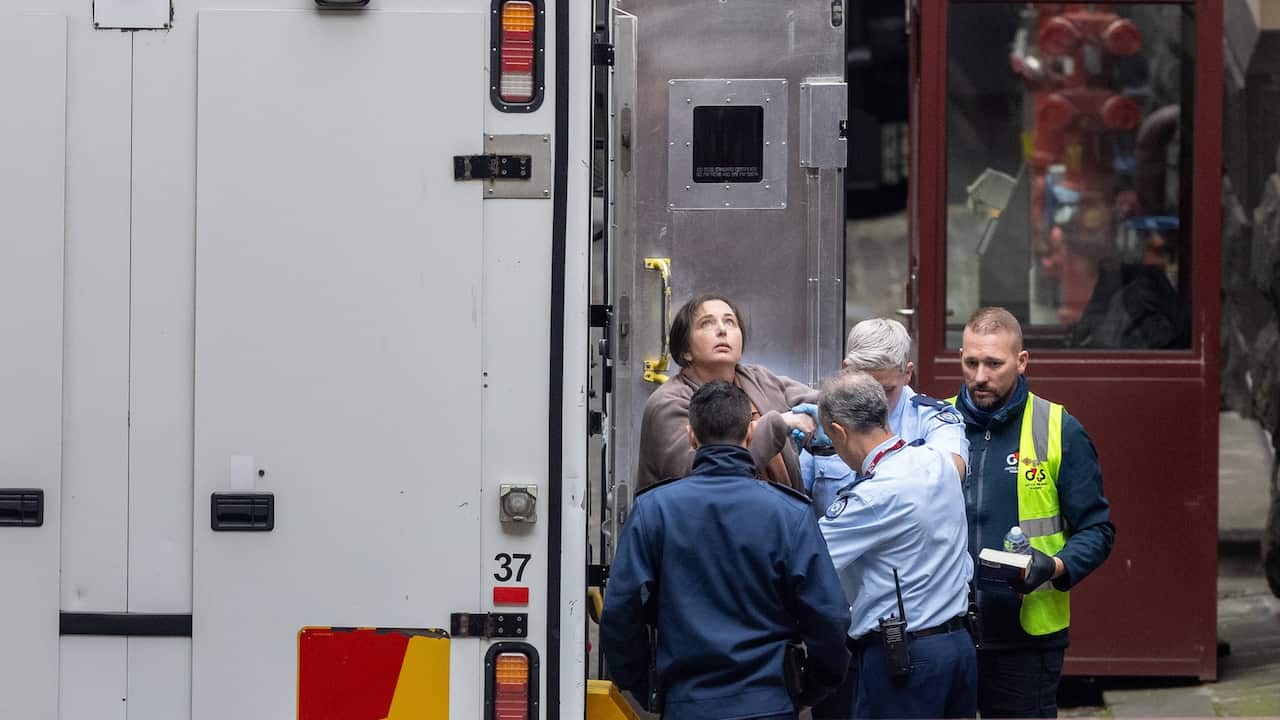 Erin Patterson, surrounded by guards, looking up at the sky.